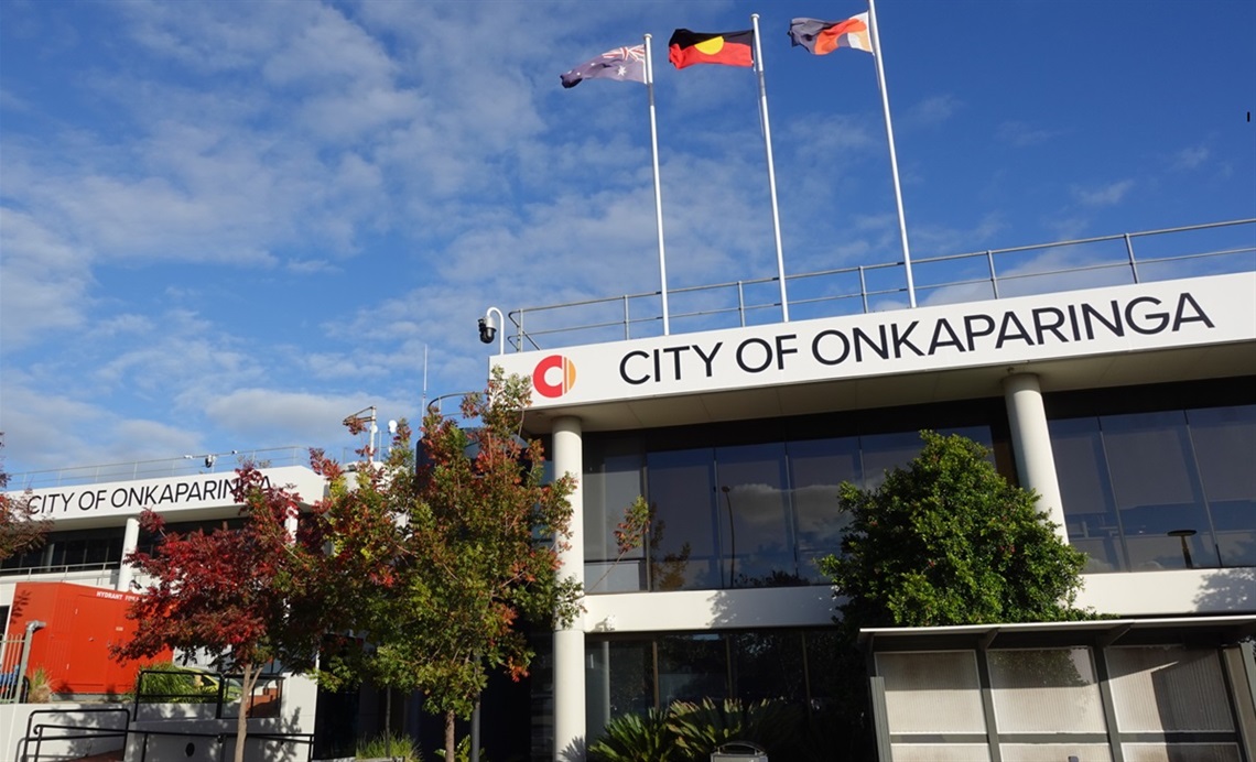 A view from outside the City of Onkaparinga's Noarlunga office showing flags flying above a council sign.