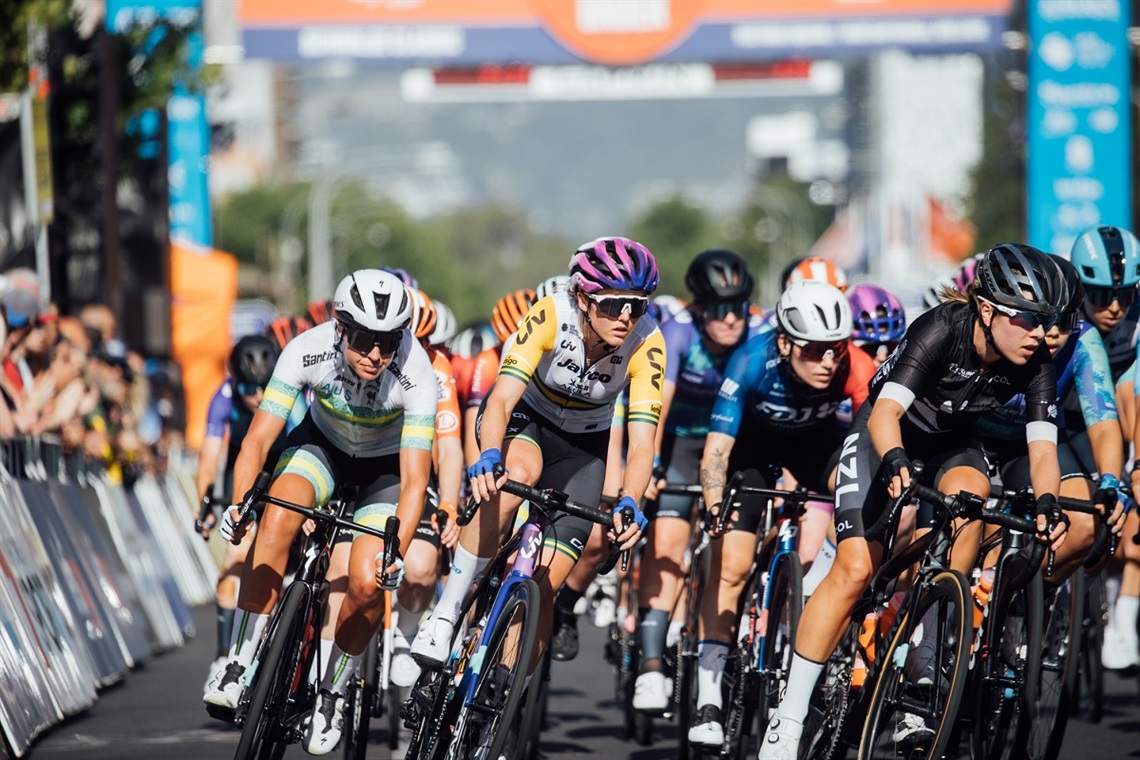 A tight peloton of women riders round a corner during the 2023 Santos Tour Down Under.