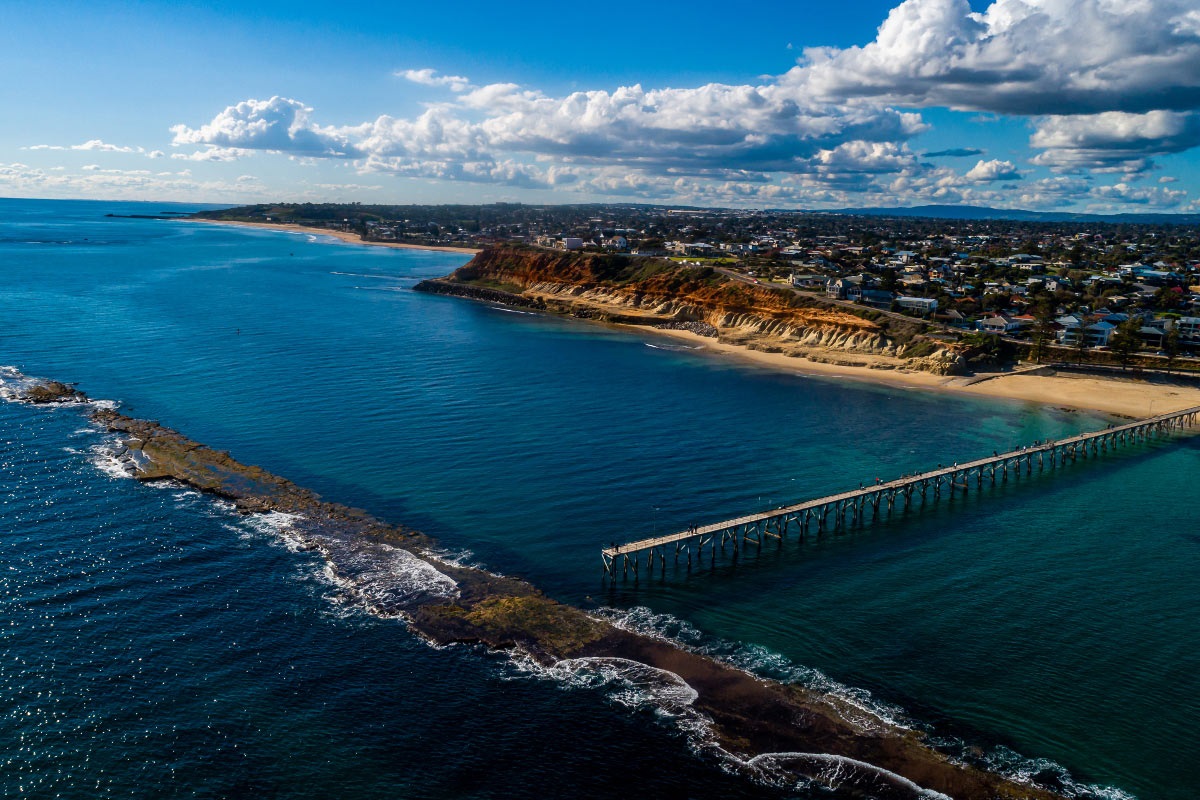 An aerial view of the Port Noarlunga jetty, ocean and coastline.