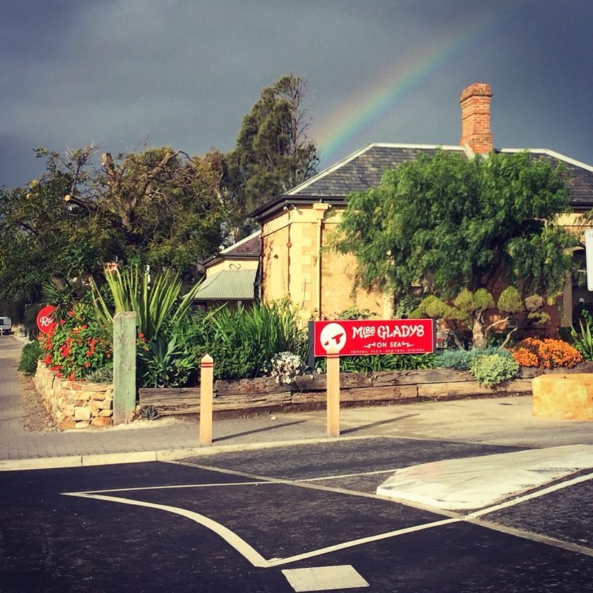 A rainbow pierces the grey sky above the Miss Gladys On Sea shop.